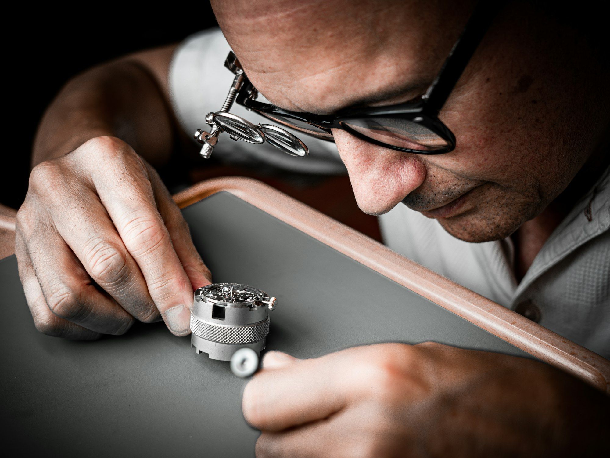 Un horloger examine le mouvement d’une montre à la loupe